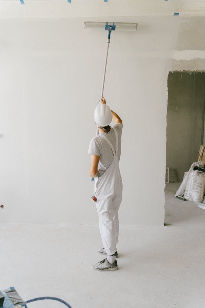 Back View of a Person Painting the Wall Using a Painting Brush Roller